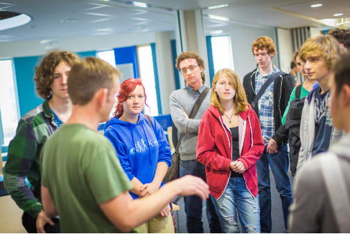 Lecturer talking to group of students at social event
